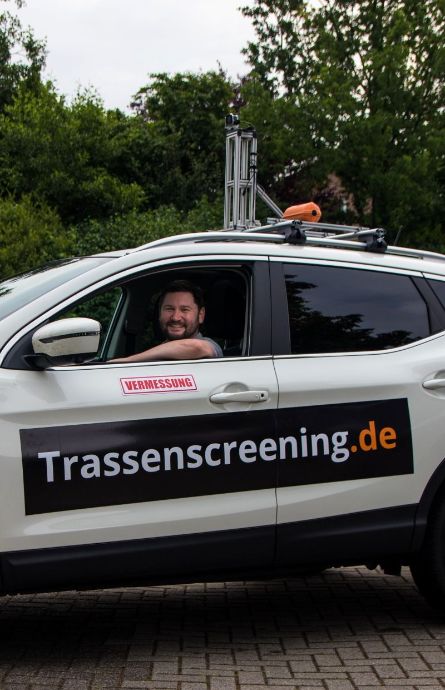Auf dem Dach des Autos ist eine Kamerainstallation zum Trassenscreening und der anschließenden Netzplanung zu sehen. Außerdem sind einige Aufkleber angebracht und ein Mitarbeiter der WiR Solutions sitzt am Steuer.